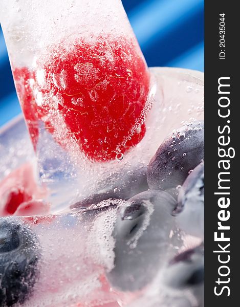 Raspberry and blackberry frozen in ice sticks with drink