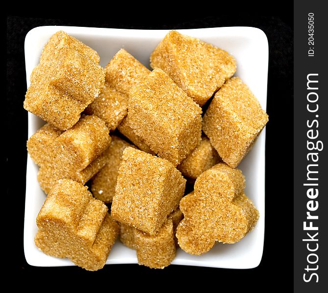 Brown sugar in a white bowl on black background