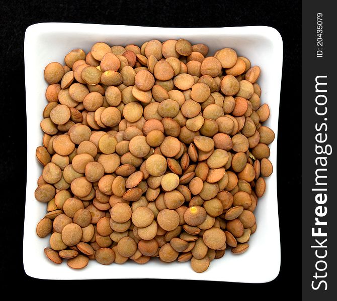 Lentil in a white bowl isolated on black