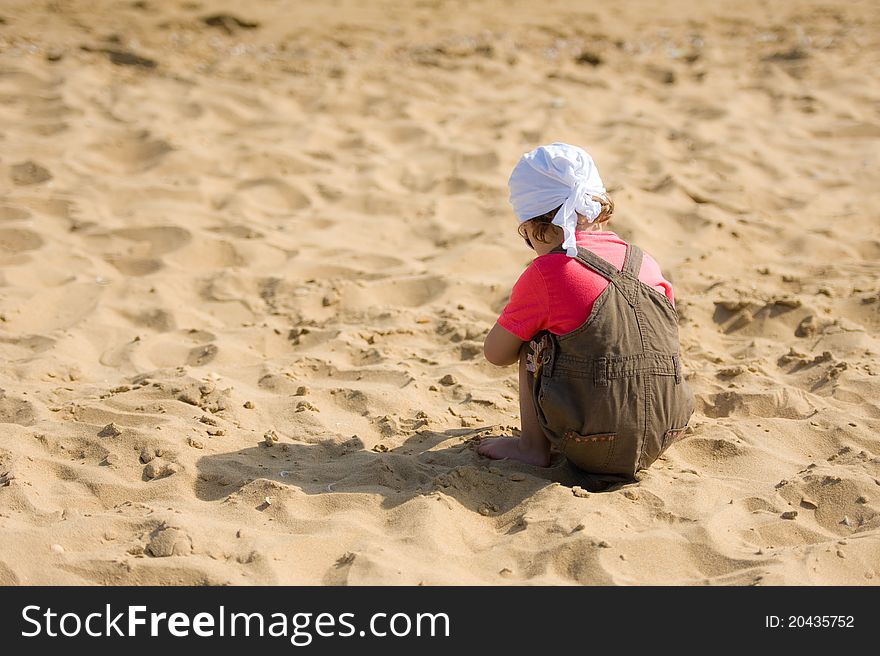 Little Child On The Beach Is Looking For Shells