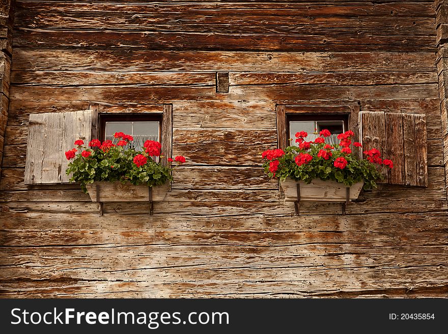 Old wooden house with geranium at the windows. Old wooden house with geranium at the windows