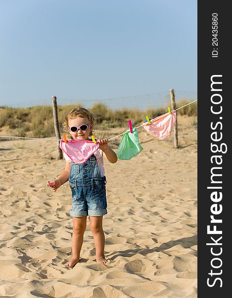 Little Baby Is Hanging Laundry On The Beach