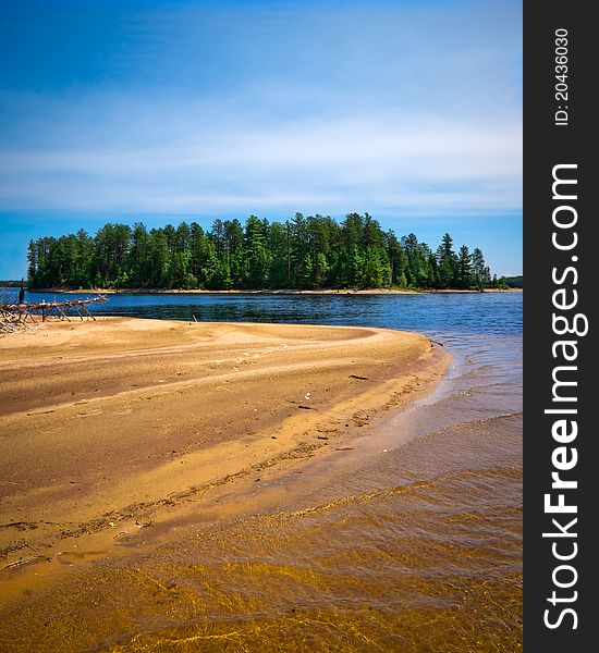 A sandbar beach juts out into the blue waters of a northern lake in the La VÃ©rendrye Wildlife Reserve in Quebec Canada. A sandbar beach juts out into the blue waters of a northern lake in the La VÃ©rendrye Wildlife Reserve in Quebec Canada.