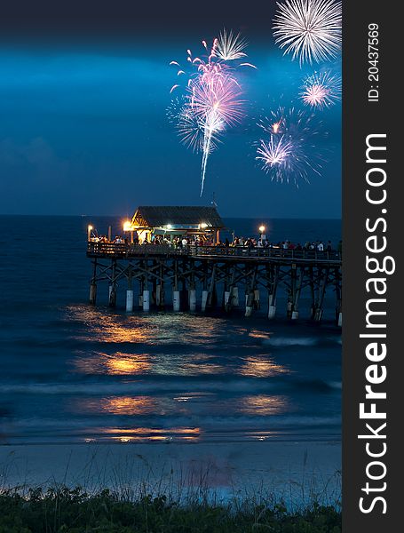 Fireworks over a pier with lights a people celebrating. Fireworks over a pier with lights a people celebrating