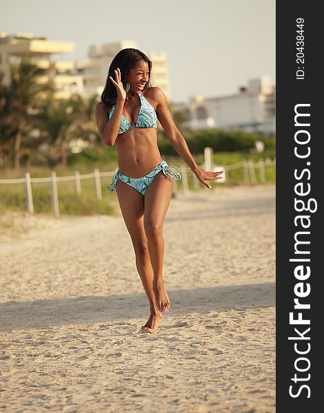 Image of a black woman waving and running on the beach. Image of a black woman waving and running on the beach