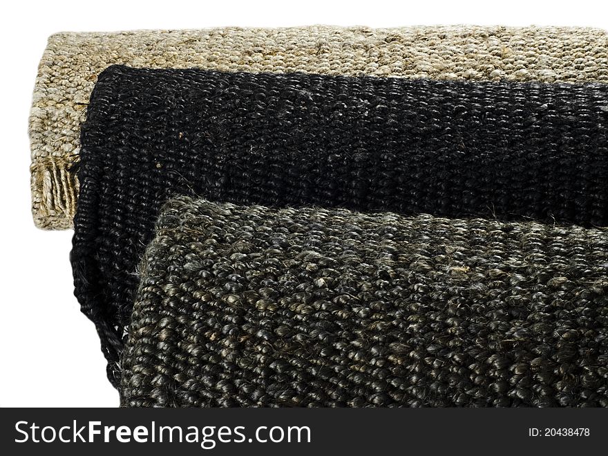 Brown, black and beige (natural) hemp rugs rolled up and arranged in lines. Brown, black and beige (natural) hemp rugs rolled up and arranged in lines
