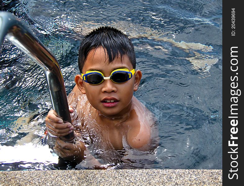 Asian boy wearing eye glass in swimming pool. Asian boy wearing eye glass in swimming pool