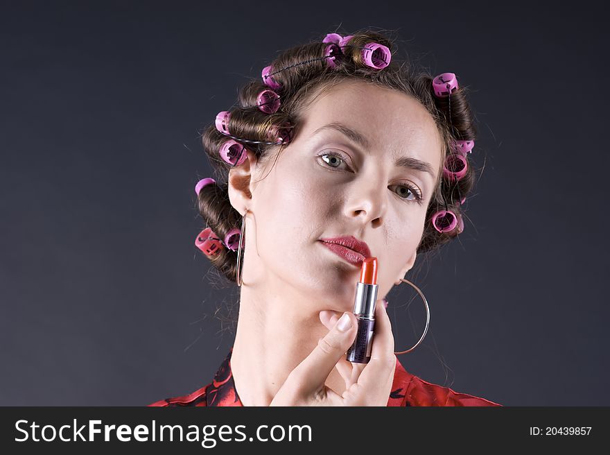 Portrait of a young beautiful woman with bigoudi on the hair on a gray background closeup. Portrait of a young beautiful woman with bigoudi on the hair on a gray background closeup