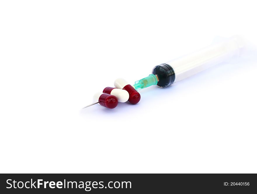 Medical pills and syringe on white background.