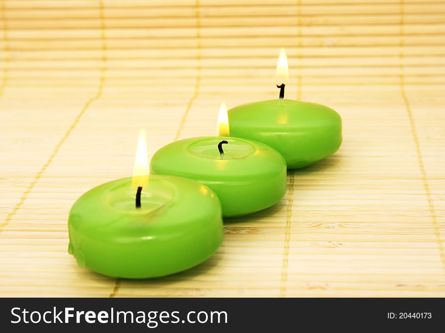 Green candles on bamboo background.