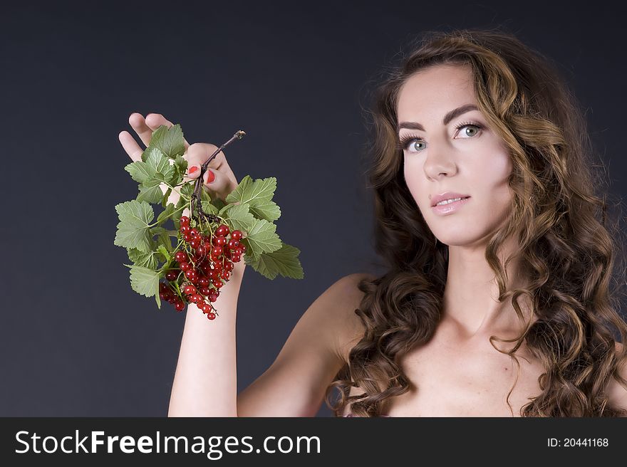 Portrait of a young beautiful woman with berries red currant on a gray background closeup. Portrait of a young beautiful woman with berries red currant on a gray background closeup