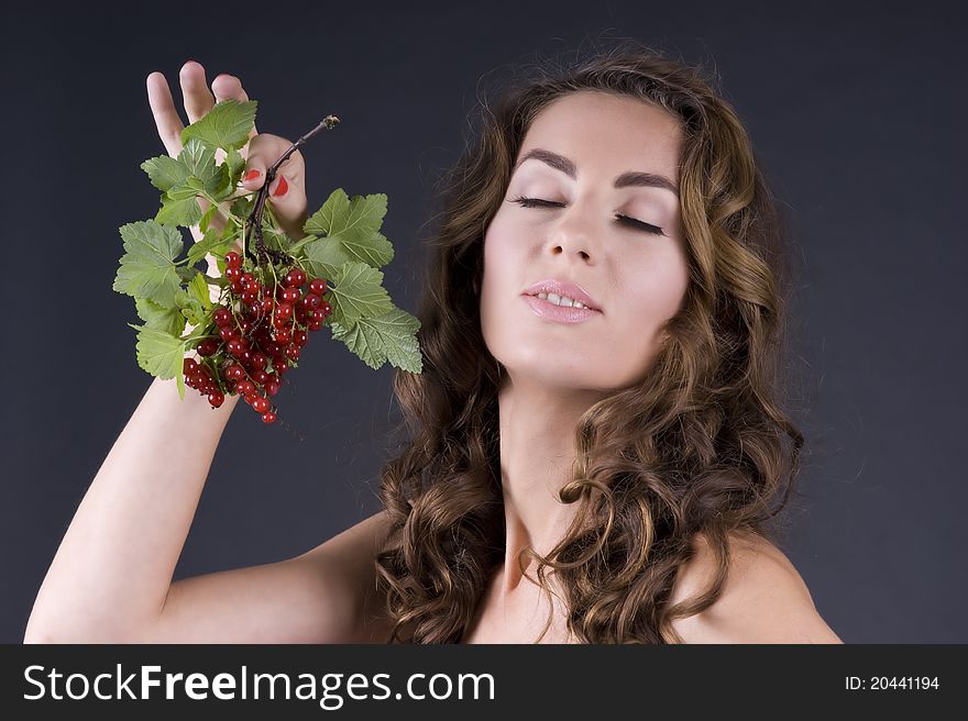 Portrait of a  young beautiful woman with berries red currant on a gray background closeup. Portrait of a  young beautiful woman with berries red currant on a gray background closeup