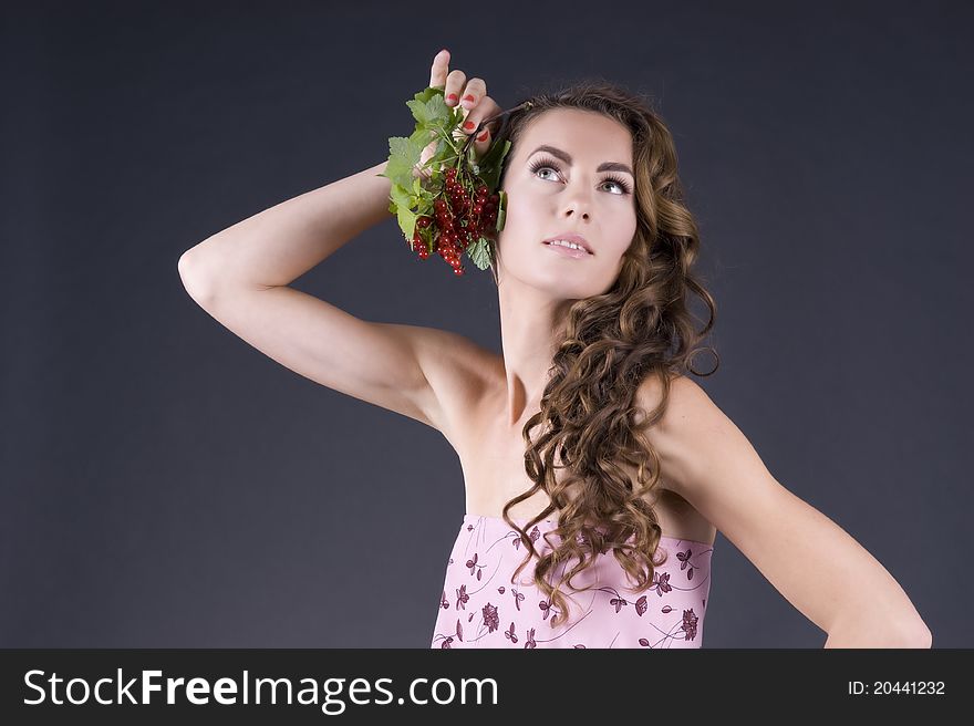 Portrait of a  young beautiful woman with berries red currant on a gray background closeup. Portrait of a  young beautiful woman with berries red currant on a gray background closeup