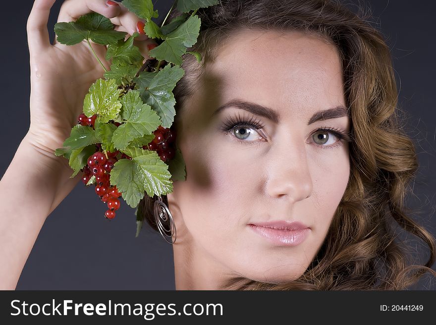 Portrait of a young beautiful woman with berries red currant on a gray background closeup. Portrait of a young beautiful woman with berries red currant on a gray background closeup