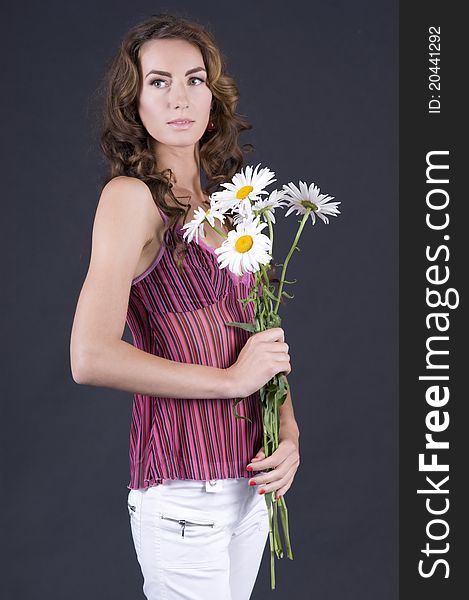 Portrait of a young beautiful woman with camomile on a gray background closeup. Portrait of a young beautiful woman with camomile on a gray background closeup