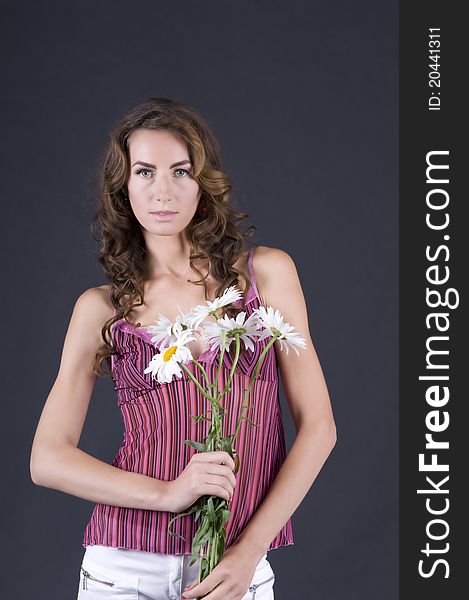 Portrait of a  young beautiful woman with camomile on a gray background closeup. Portrait of a  young beautiful woman with camomile on a gray background closeup