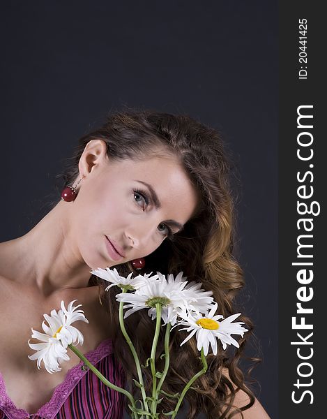 Portrait of a  young beautiful woman with camomile on a gray background closeup. Portrait of a  young beautiful woman with camomile on a gray background closeup