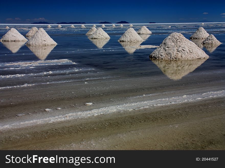 The endless flats of Salar de Uyuni, Bolivia. It was strange enough to see the lake covered in water as it was wet season, but the piles of salt extracted from the lake make it the most surreal place.