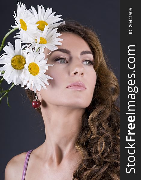 Portrait of a young beautiful woman with camomile on a gray background closeup. Portrait of a young beautiful woman with camomile on a gray background closeup