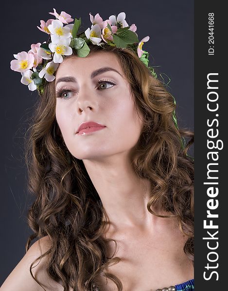 Portrait of a beautiful girl with flowers in hair on a gray background closeup