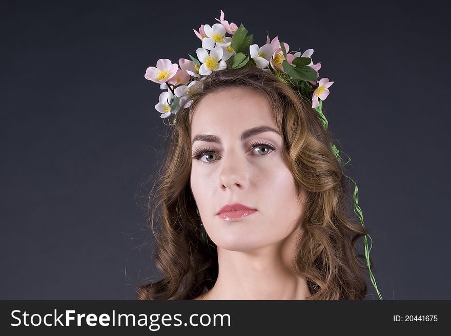 Portrait of a  beautiful girl with flowers in hair on a gray background closeup