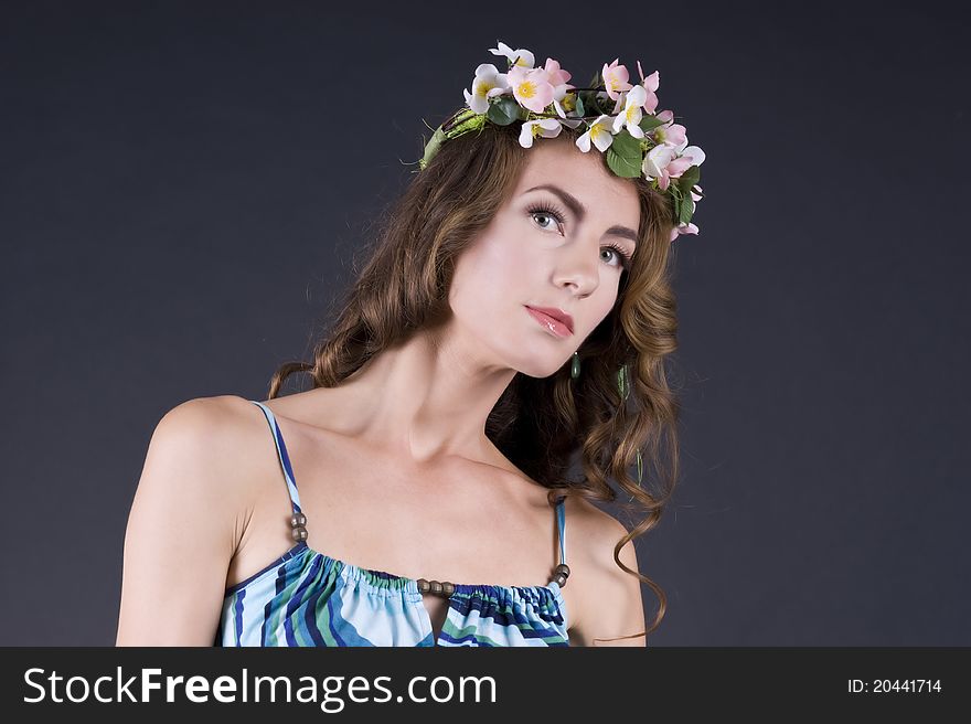 Portrait of a  beautiful girl with flowers in hair on a gray background closeup