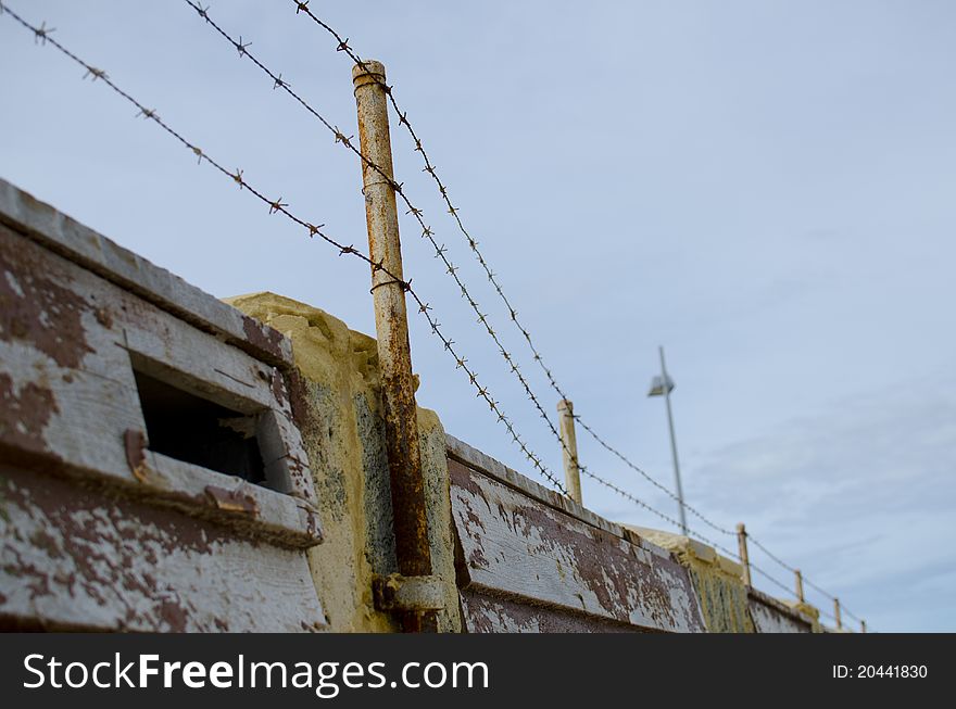 A barb wire security fence on top of a wall around a heavily secured property.