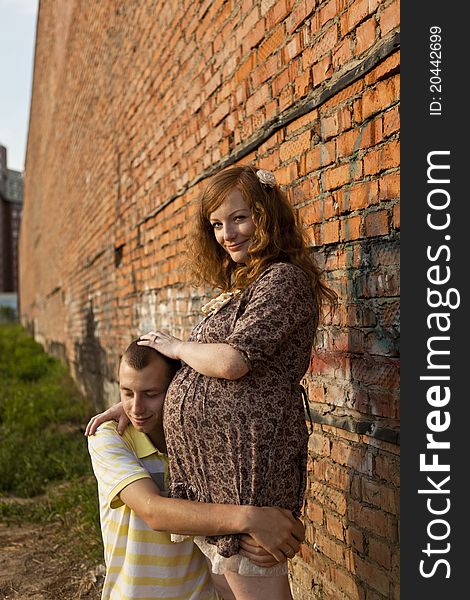 Portrait of a happy young man kisses his pregnant wife . outdoor .