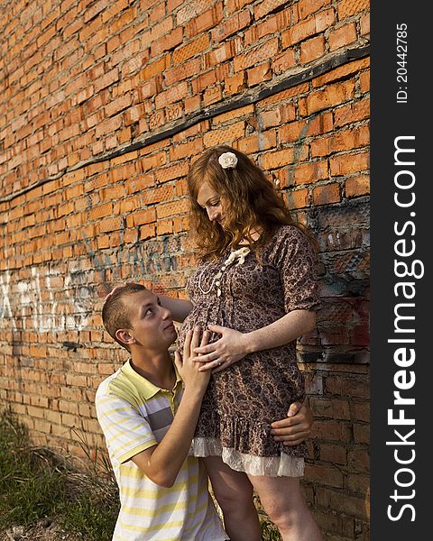 Portrait of a happy young man kisses his pregnant wife . outdoor .