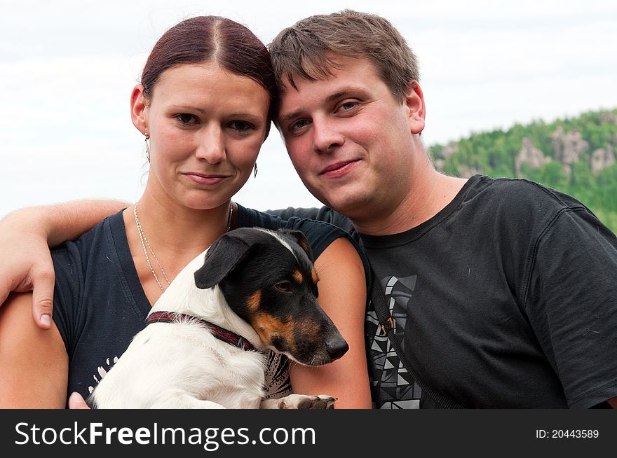 Young couple with beautiful dog posing outdoor.