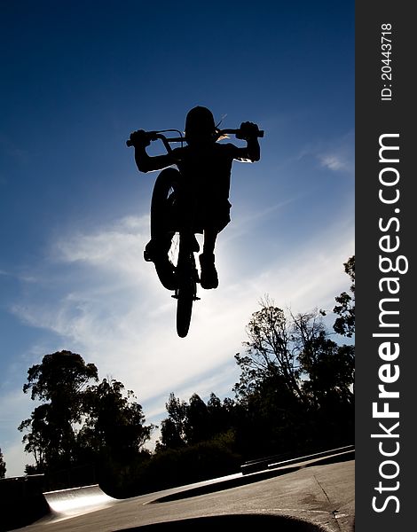 Silhouette of Freestyle BMX rider getting air at a skate park