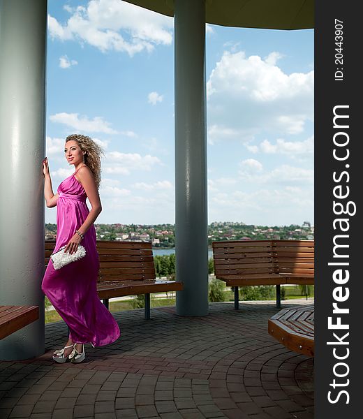 Woman in a pink dress stands near the column