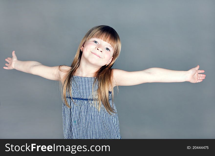 The little girl in a dress smiles happily spreading his hands. The little girl in a dress smiles happily spreading his hands