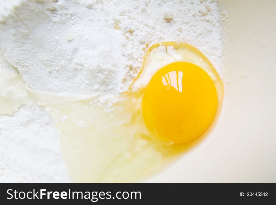 A cracked egg in a well of sifted flour. A cracked egg in a well of sifted flour