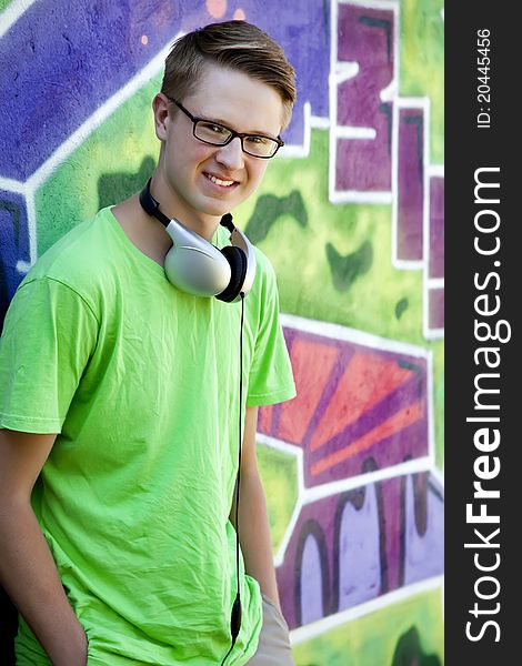 Teen Boy With Earphones Near Graffiti Wall.