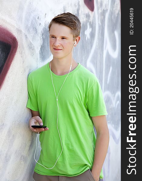 Teen Boy With Earphones Near Graffiti Wall.