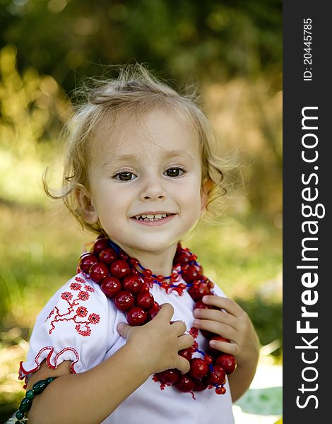 Little girl in traditional ukrainian costume on green grass at the park.