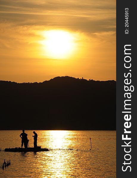 Three people preparing their bait before fishing on sunset. Three people preparing their bait before fishing on sunset