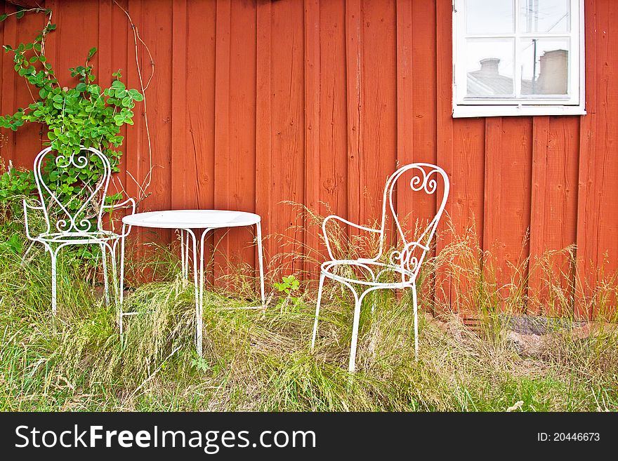 Two chairs in front of a wall, on tall grass. Two chairs in front of a wall, on tall grass.