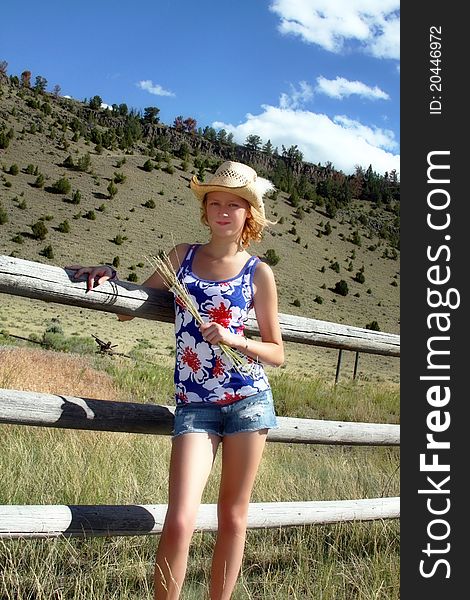 Happy young teen girl wearing cowgirl hat and standing in the wide open spaces of the United States west. Happy young teen girl wearing cowgirl hat and standing in the wide open spaces of the United States west.
