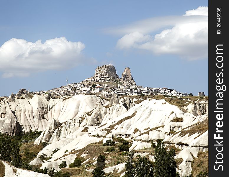 Uchisar on top of limestone terrain viewd from Goreme, square format, copy space, crop are, blue sky with white clouds. Uchisar on top of limestone terrain viewd from Goreme, square format, copy space, crop are, blue sky with white clouds