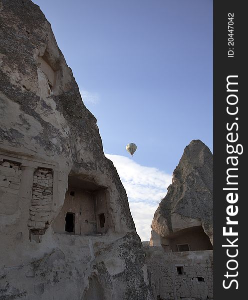 Limestone home typical of the Cappadocia region in Turkey, caves carved from limestone with a hot air balloon as a backdrop, portrait, copy space. Limestone home typical of the Cappadocia region in Turkey, caves carved from limestone with a hot air balloon as a backdrop, portrait, copy space