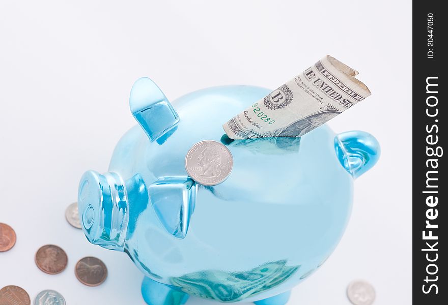 Metallic blue piggy bank and money ready to go inside it; selective focus on the dollars. Metallic blue piggy bank and money ready to go inside it; selective focus on the dollars