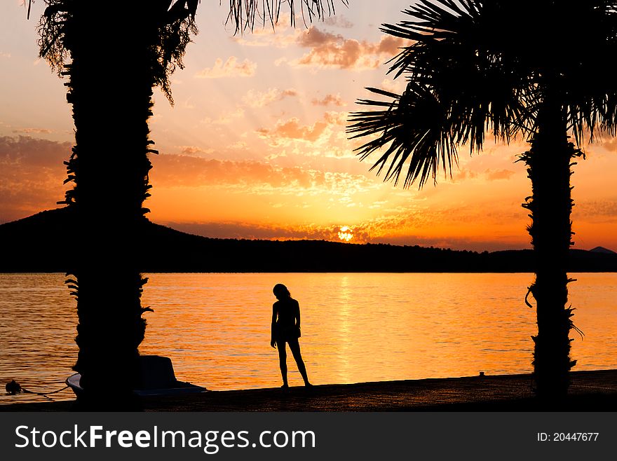 Girl silhouette on sunset background