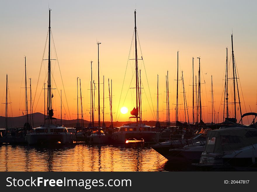 Sailing boats in marina at sunset