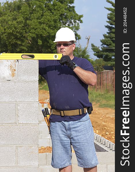 Supervisor checking cinder block where masons are building walls. Supervisor checking cinder block where masons are building walls