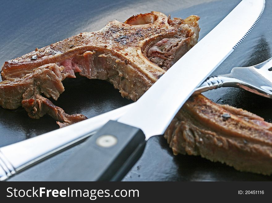 T-bone on empty dinner plate with fork and steak knife. T-bone on empty dinner plate with fork and steak knife