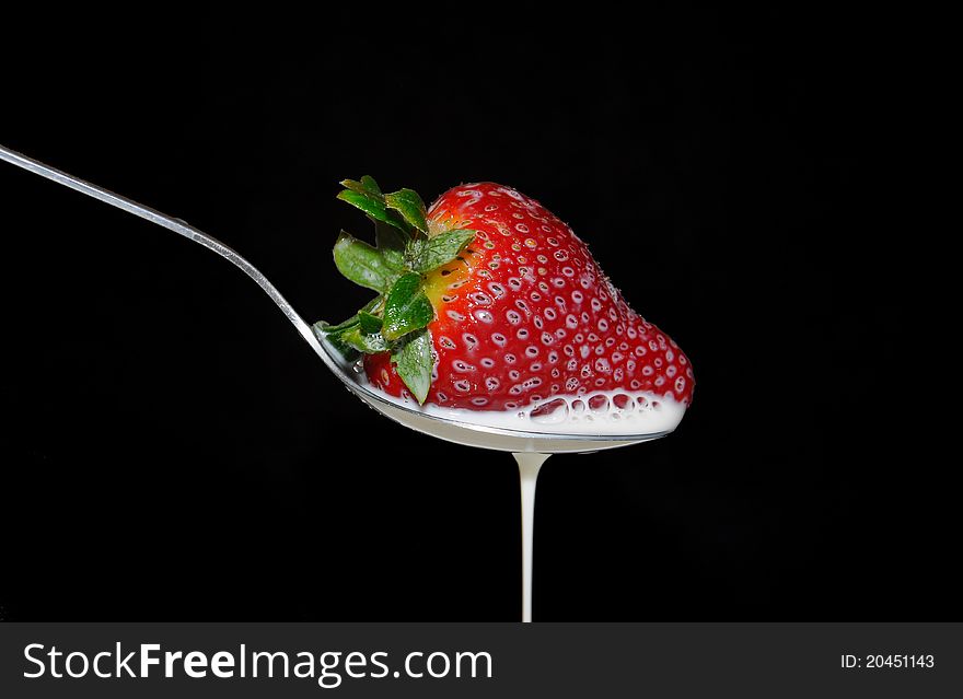 Spoon with strawberry and milk on a black background. Spoon with strawberry and milk on a black background