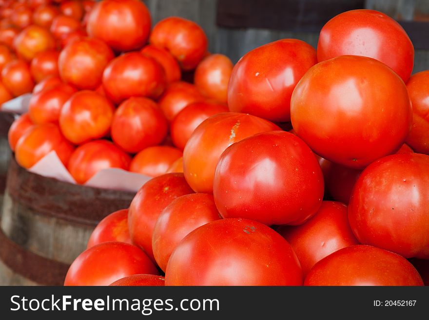 Fresh tomatoes in barrels at a farmer's produce stand.