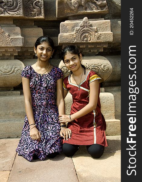 Two smiling sisters sitting at the backdrop of temple at Pattadakal in Bagalkot district, Karnataka, India, Asia. Two smiling sisters sitting at the backdrop of temple at Pattadakal in Bagalkot district, Karnataka, India, Asia